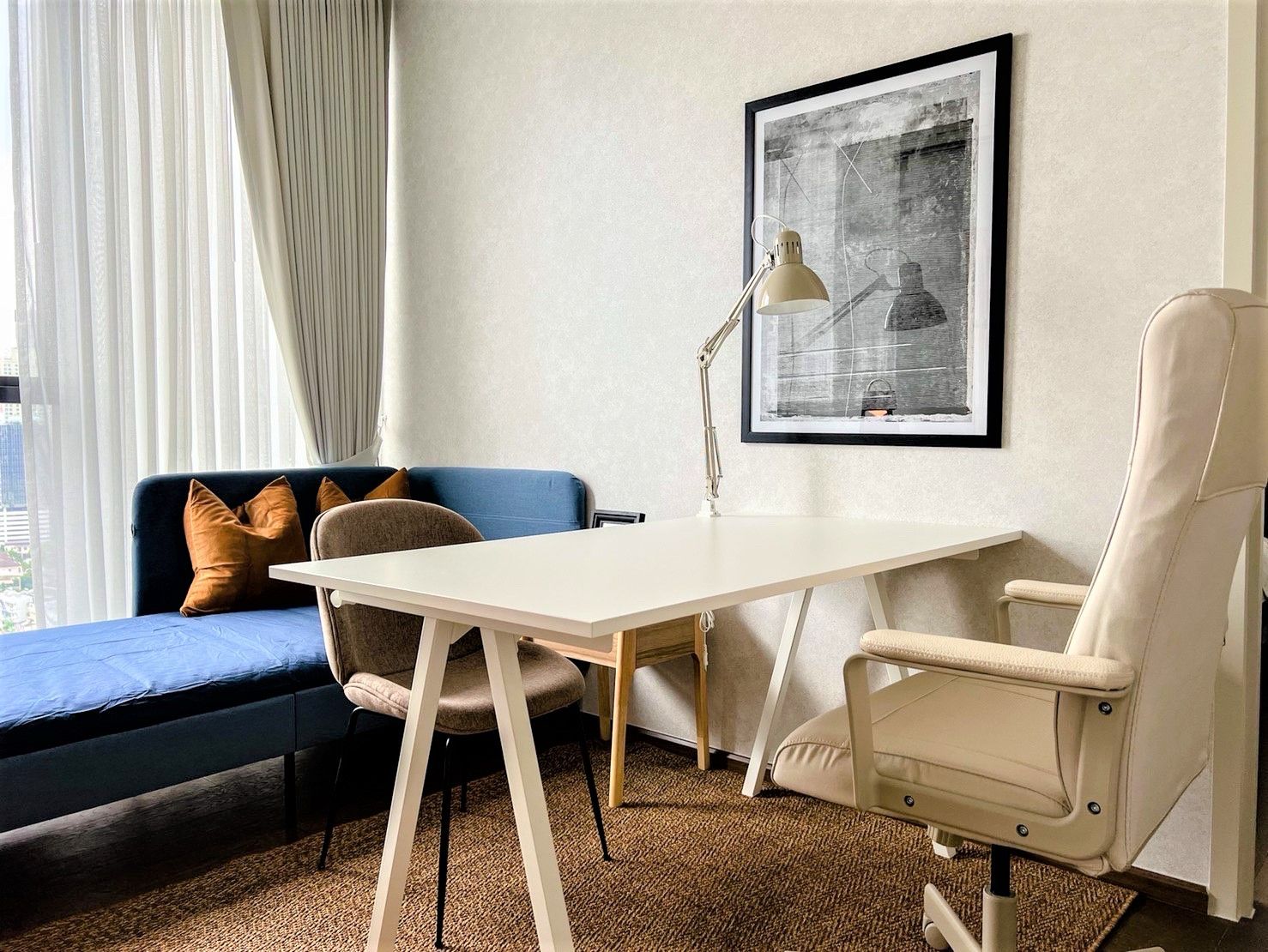 Workspace with white desk, chairs, and daybed in a modern setup.