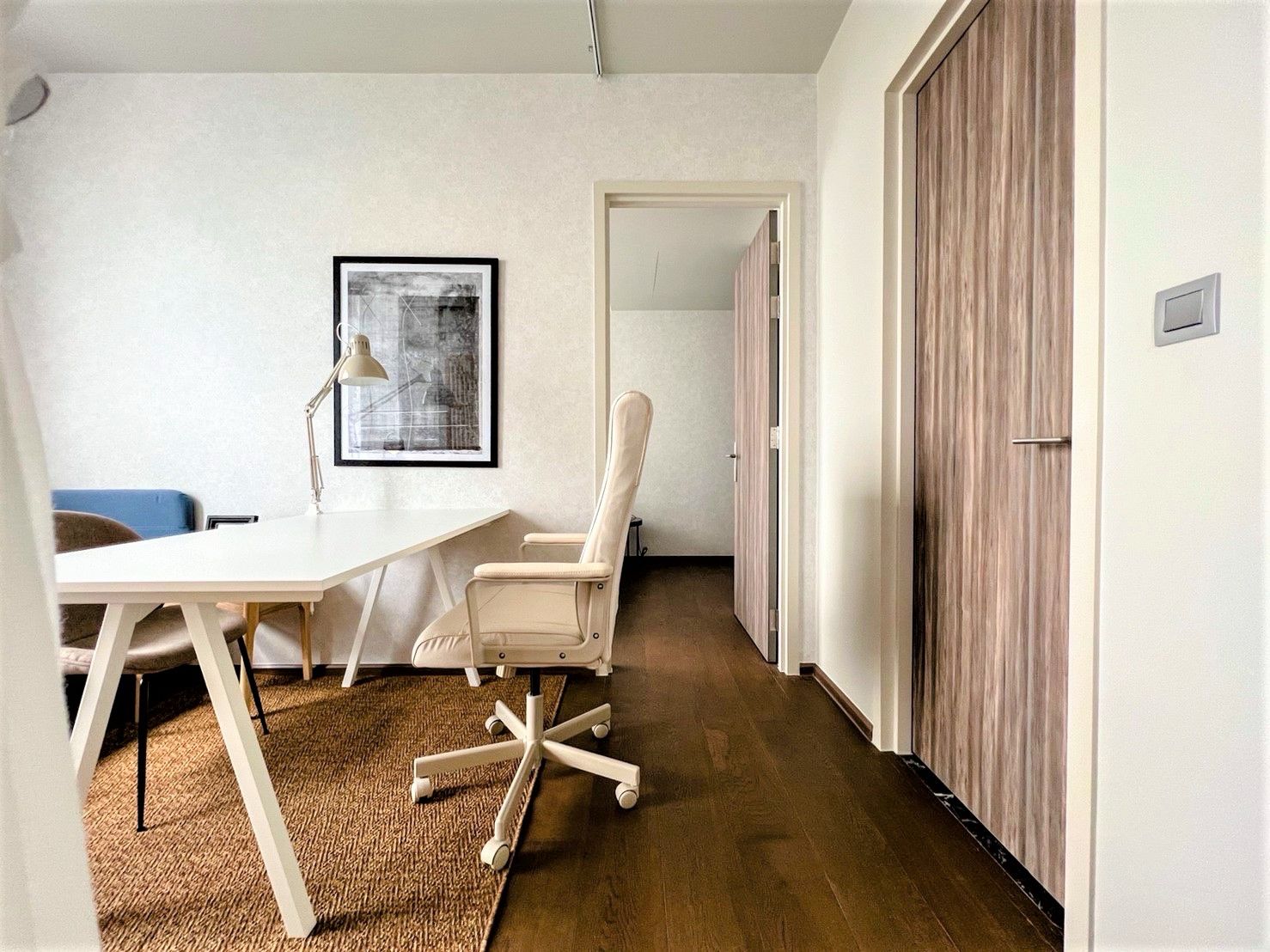 Modern office space with white desk, ergonomic chair, and wall art.