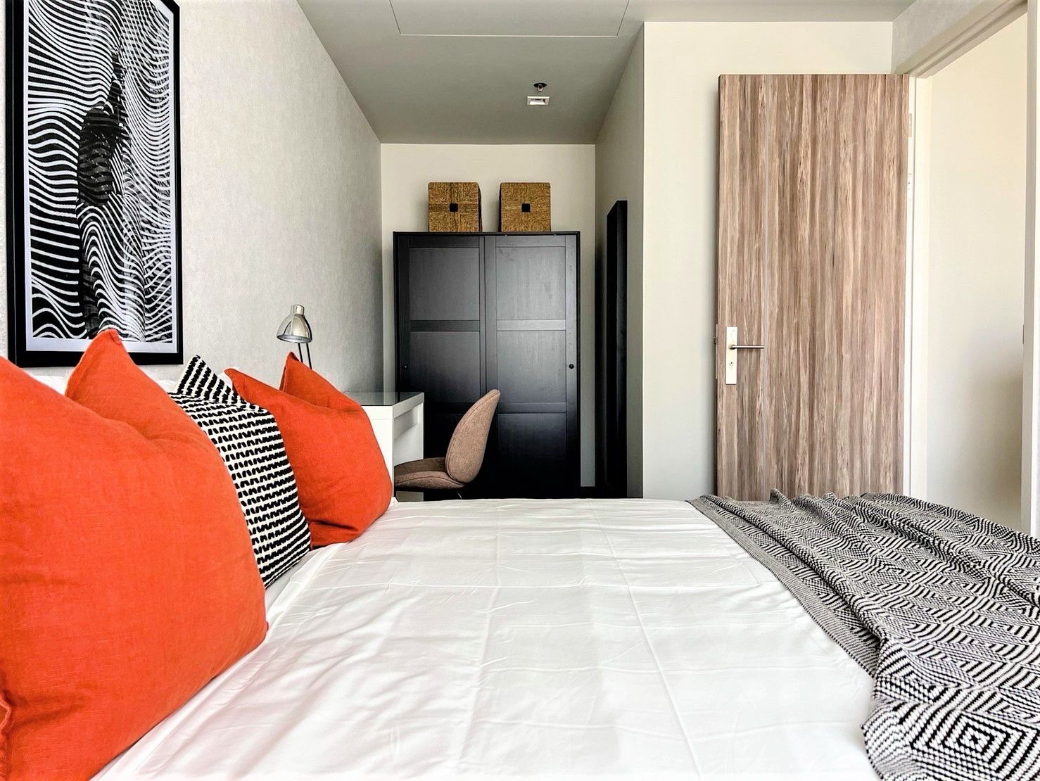 Bedroom with bed, vibrant pillows, and wall art in a cozy modern design.