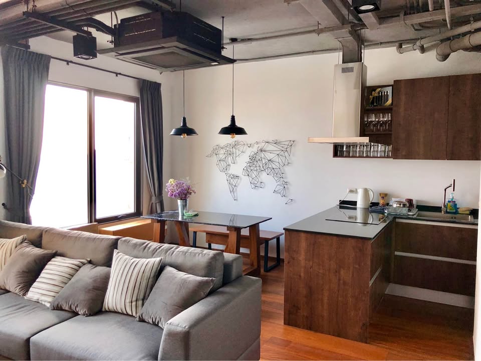 Spacious loft-style 1-bedroom duplex at Villa Asoke with high ceilings, floor-to-ceiling windows, modern furnishings, and city skyline views in Bangkok.