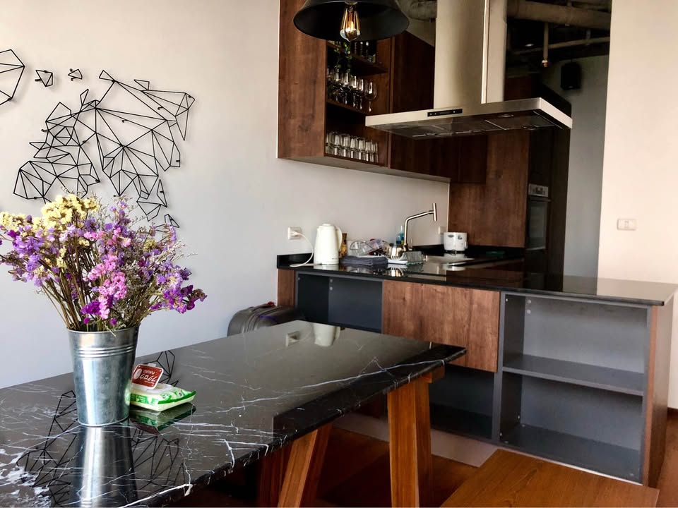 Spacious loft-style 1-bedroom duplex at Villa Asoke with high ceilings, floor-to-ceiling windows, modern furnishings, and city skyline views in Bangkok.