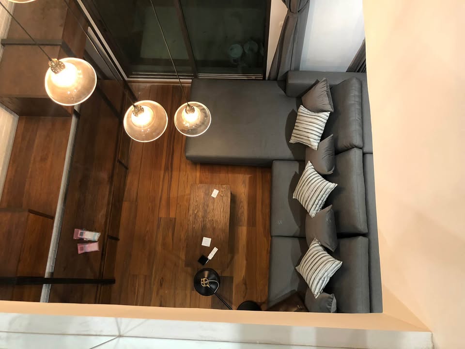Spacious loft-style 1-bedroom duplex at Villa Asoke with high ceilings, floor-to-ceiling windows, modern furnishings, and city skyline views in Bangkok.