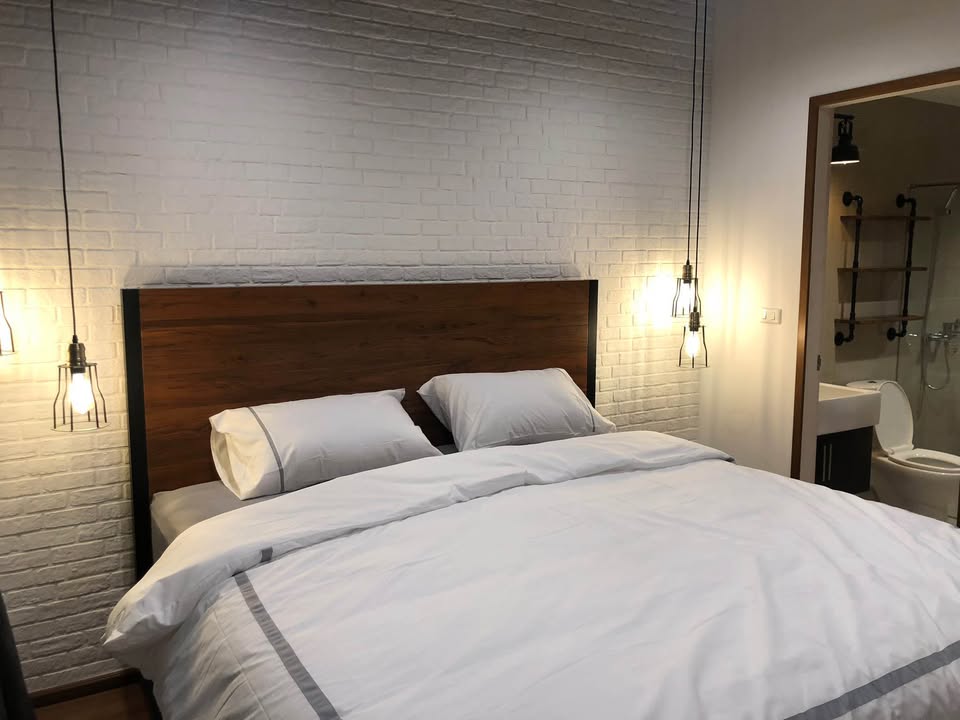Spacious loft-style 1-bedroom duplex at Villa Asoke with high ceilings, floor-to-ceiling windows, modern furnishings, and city skyline views in Bangkok.