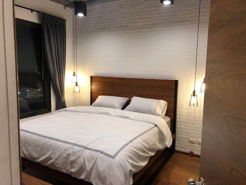 Spacious loft-style 1-bedroom duplex at Villa Asoke with high ceilings, floor-to-ceiling windows, modern furnishings, and city skyline views in Bangkok.