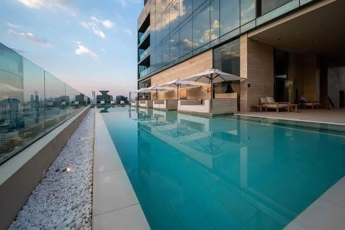 Spacious and modern living room in a 1-bedroom condo at The Strand Thonglor, featuring floor-to-ceiling windows and elegant furniture near BTS Thonglor, Bangkok.