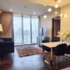 Spacious and modern living room with city views in a 2-bedroom condo at The Monument Sanampao, Bangkok, featuring elegant décor and floor-to-ceiling windows.