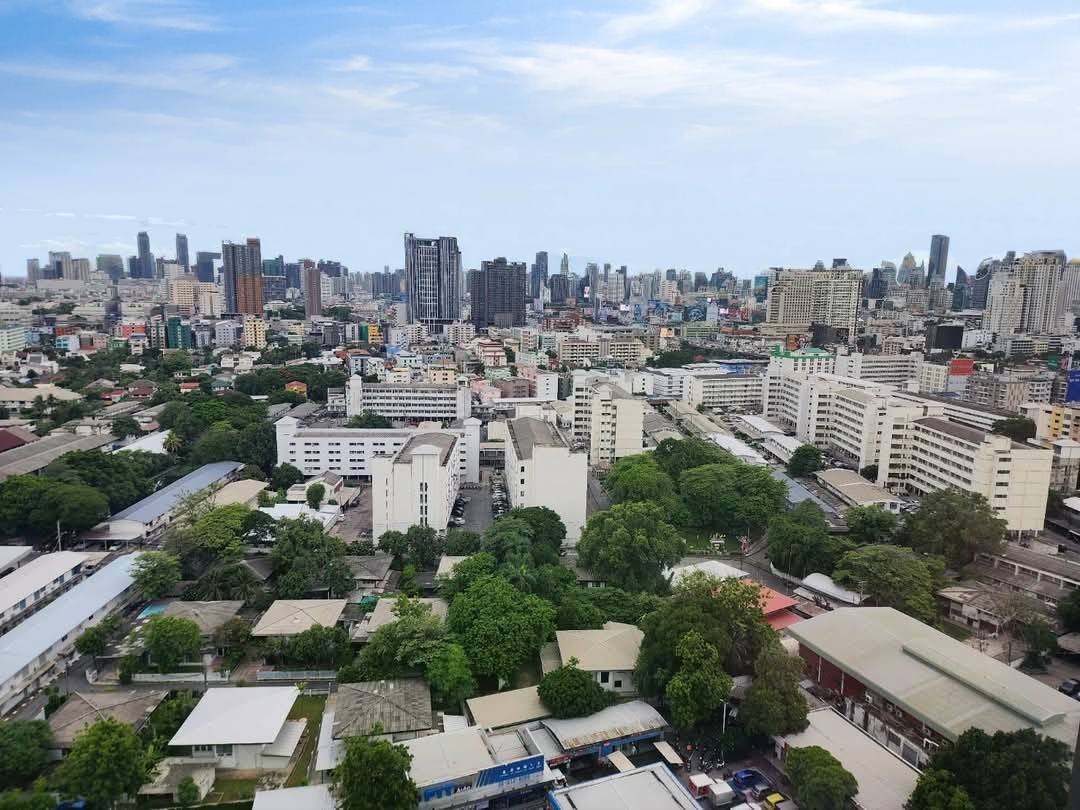 Spacious and modern living room with city views in a 2-bedroom condo at The Monument Sanampao, Bangkok, featuring elegant décor and floor-to-ceiling windows.