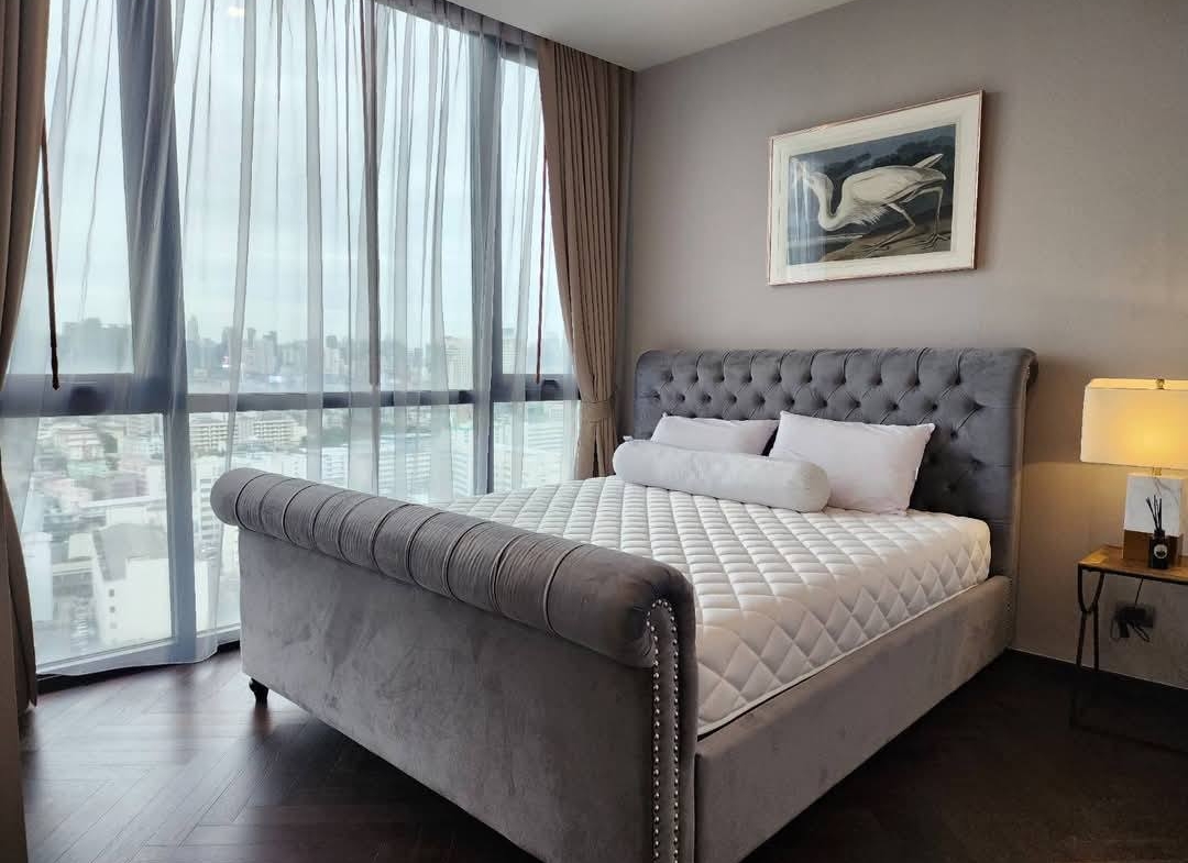 Spacious and modern living room with city views in a 2-bedroom condo at The Monument Sanampao, Bangkok, featuring elegant décor and floor-to-ceiling windows.